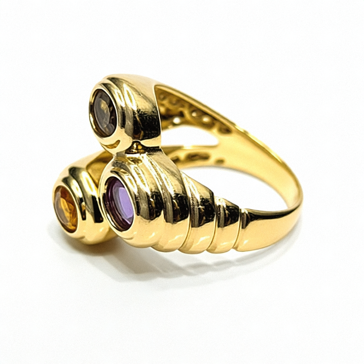 Gold ring with three gemstones on a purple surface