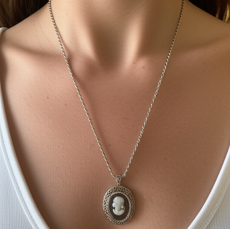 Necklace with a cameo pendant on a woman wearing a white top.