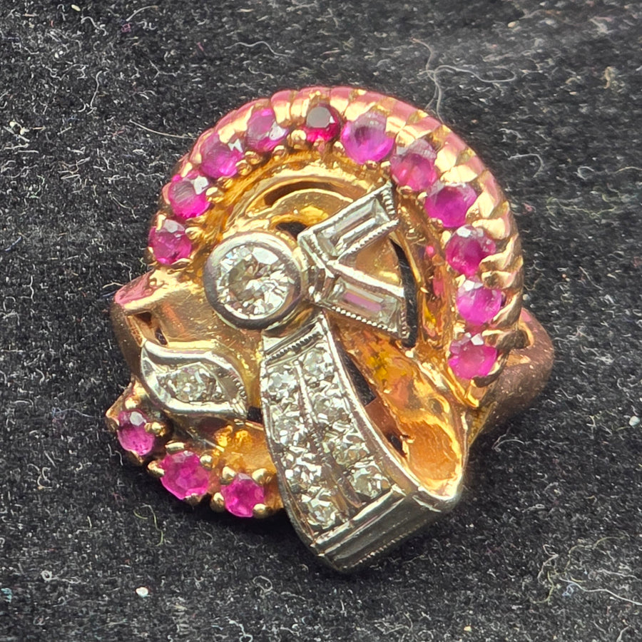 Gold brooch with red gemstones and a central diamond on a dark background