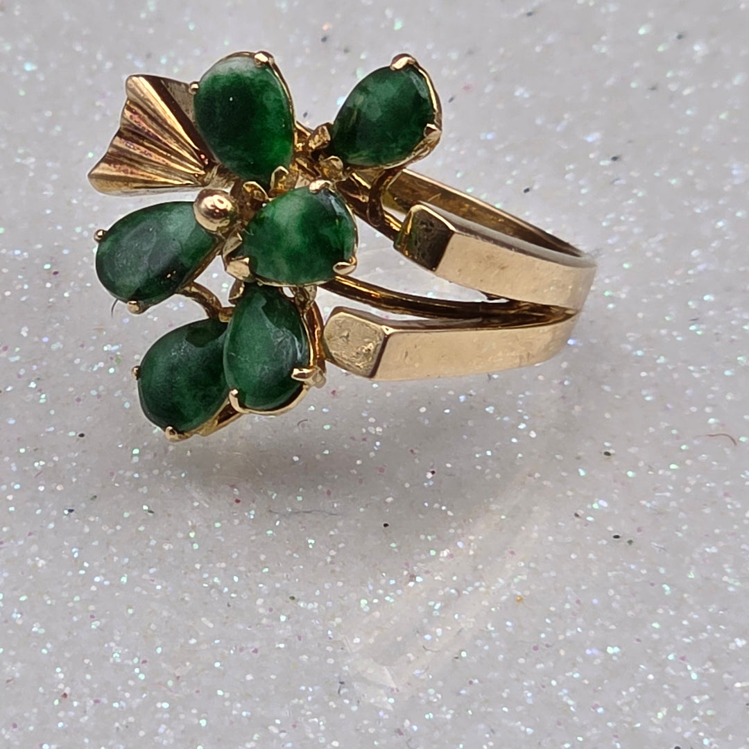 Gold earring with green gemstones on a light gray background