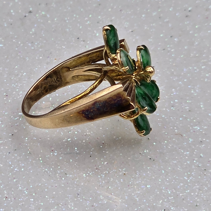 Gold ring with jade gemstones on a light gray background