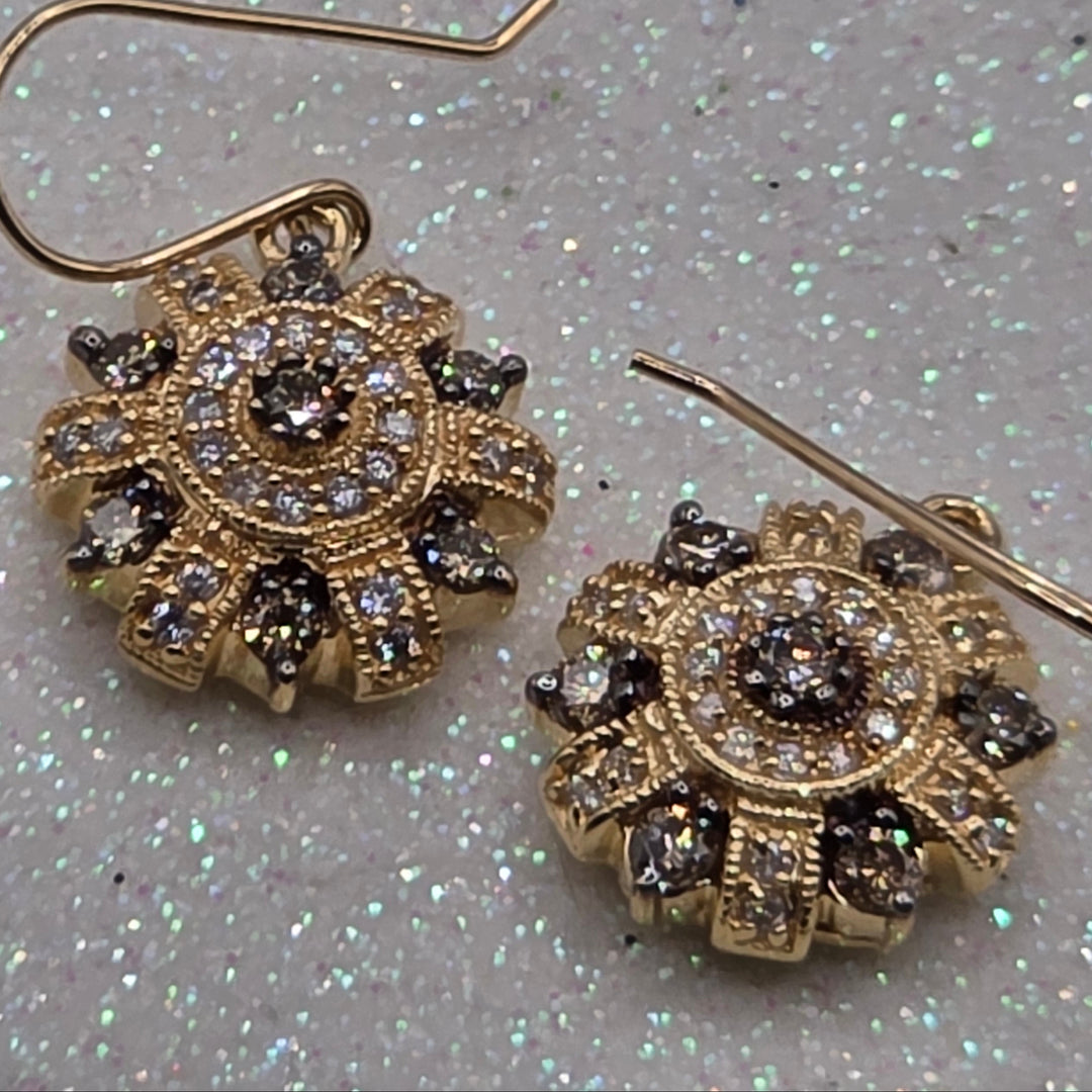 Gold earrings with gemstones on a glittery gray background