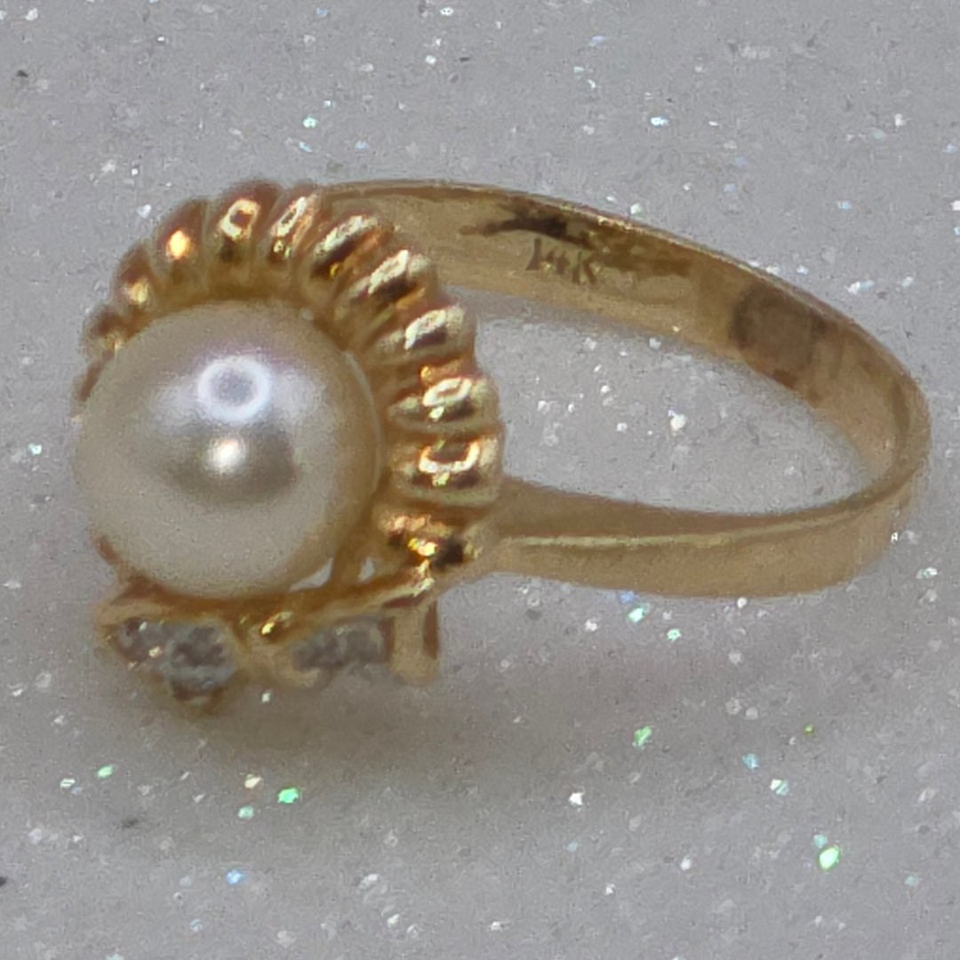 Gold ring with a pearl on a glittery gray background