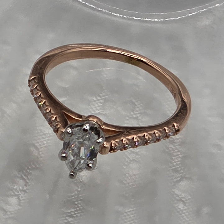 Rose gold ring with a diamond on a textured gray background