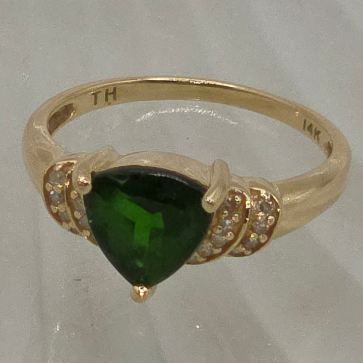 Gold ring with a green gemstone on a white background