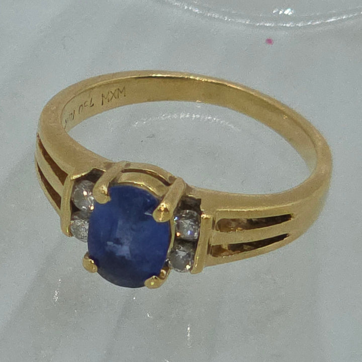 Gold ring with a blue gemstone and smaller diamonds on a white background