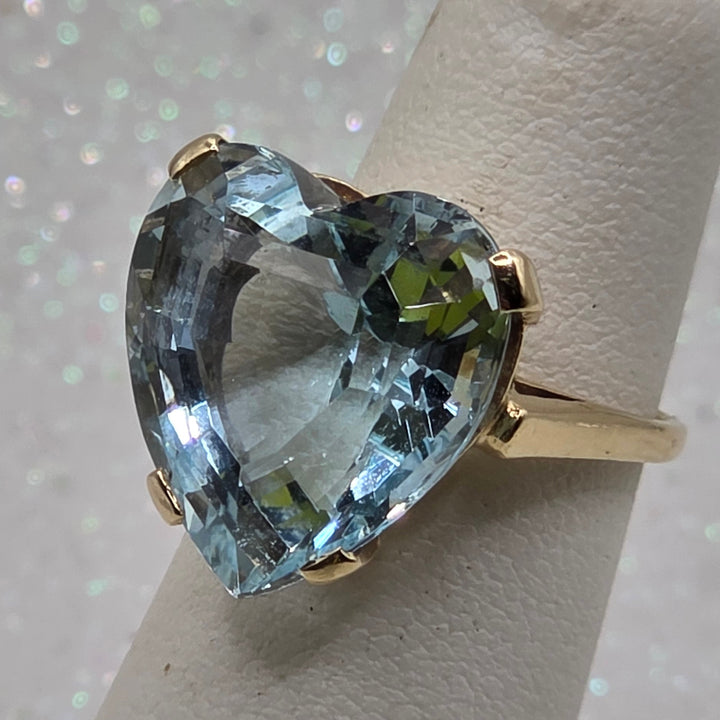 Gold ring with a large blue aquamarine gemstone on a white background