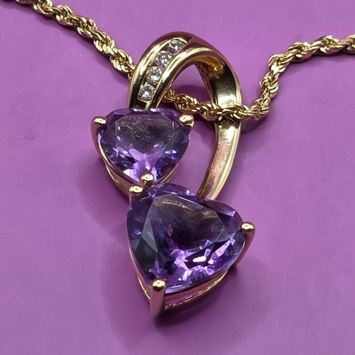 Gold necklace with purple amethyst gemstones on a purple background