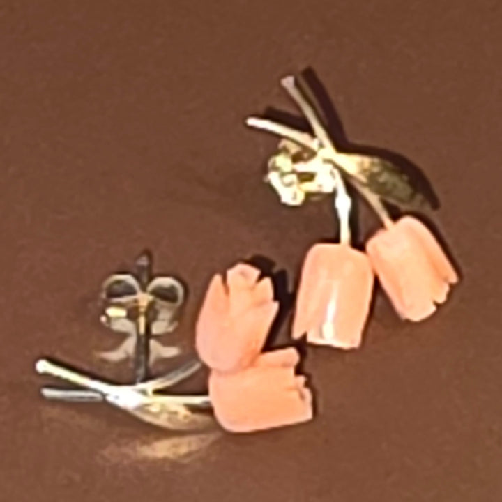 Pair of pink flower-shaped earrings on a brown background