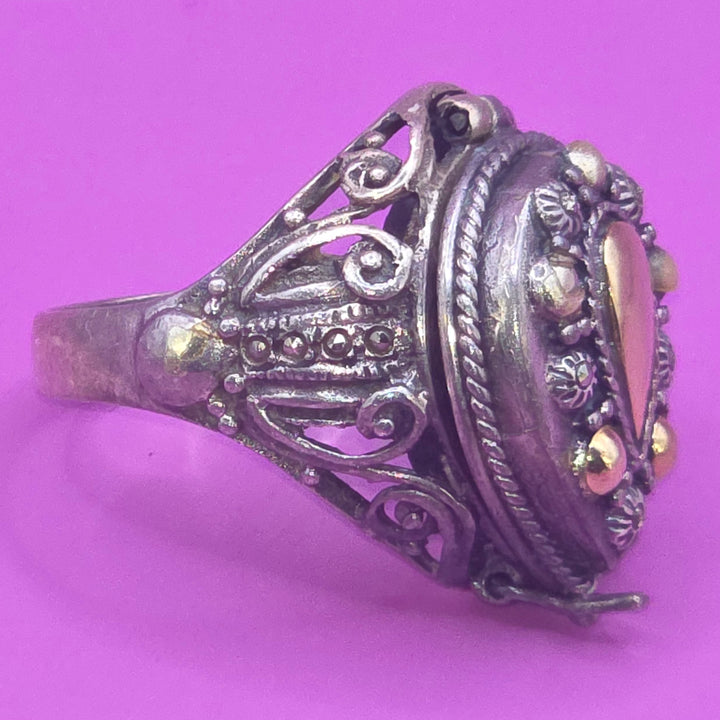 Decorative silver poison ring with gemstones on a purple background