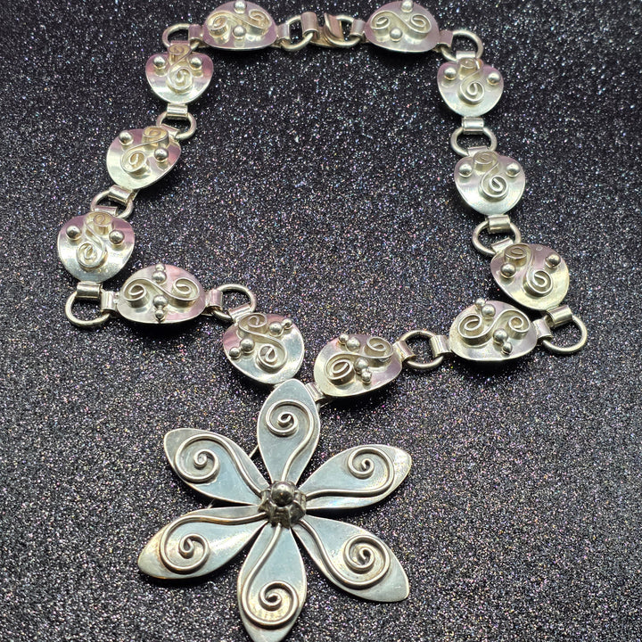 Silver bracelet with a floral clasp on a dark background