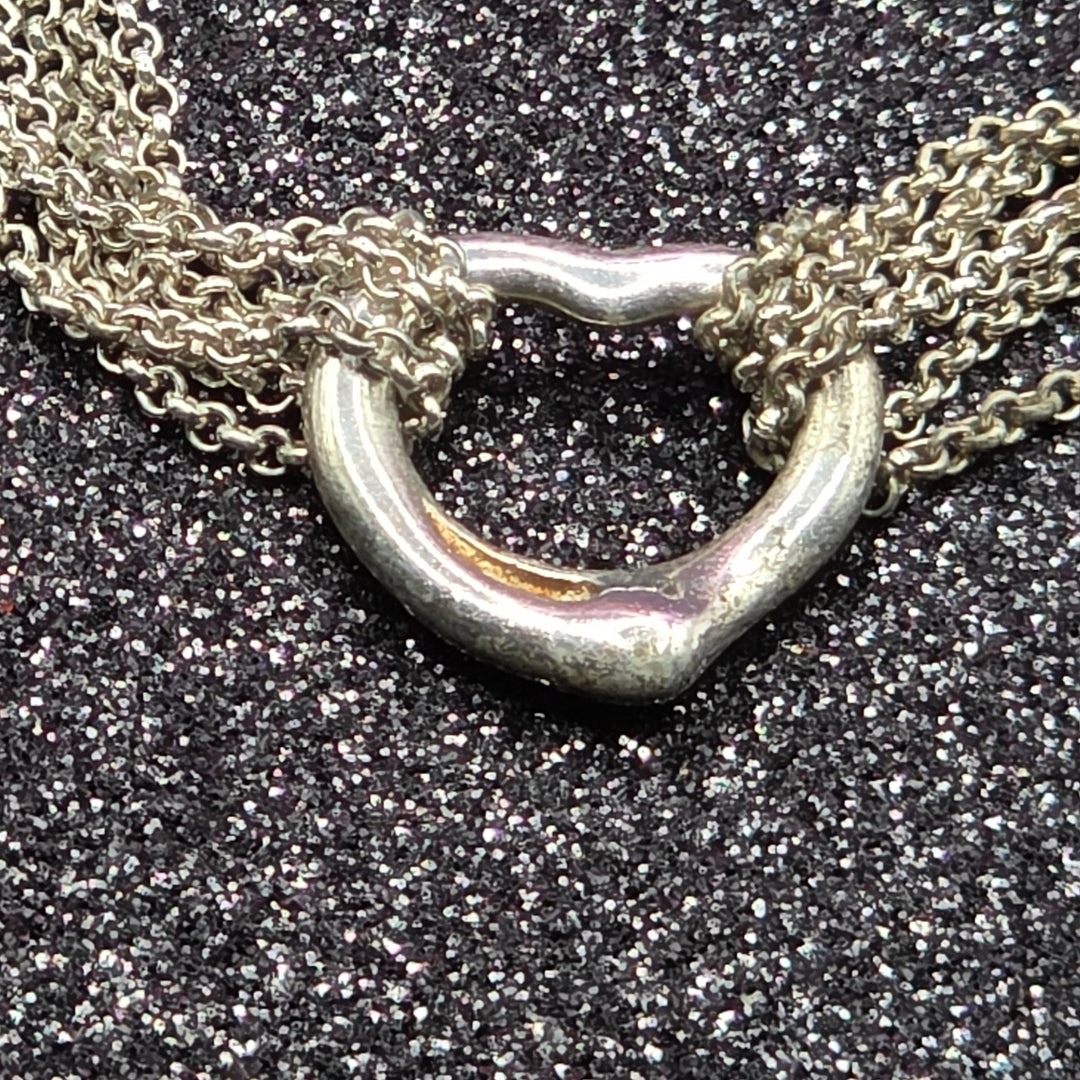Close-up of a silver necklace clasp on a textured black surface