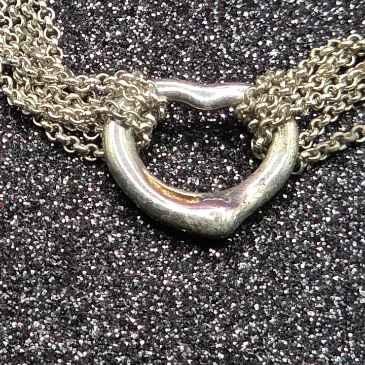 Close-up of a silver necklace clasp on a textured black surface
