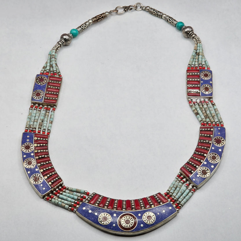 Decorative necklace with colorful beads and metal elements on a gray background