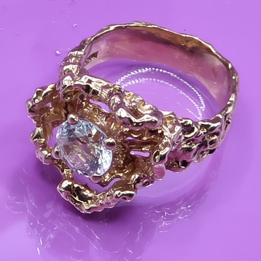 Gold ring with a quartz gemstone on a purple background