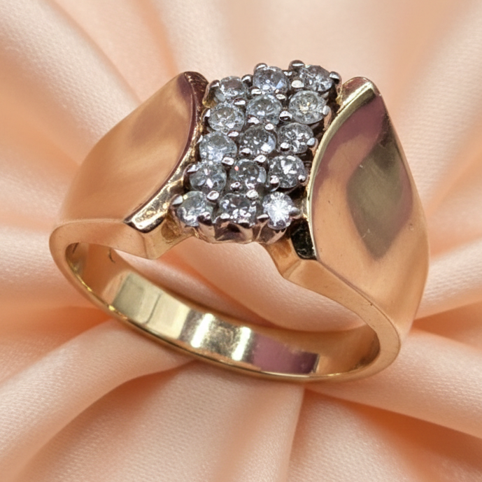 Gold ring with diamond accents on a soft pink fabric background
