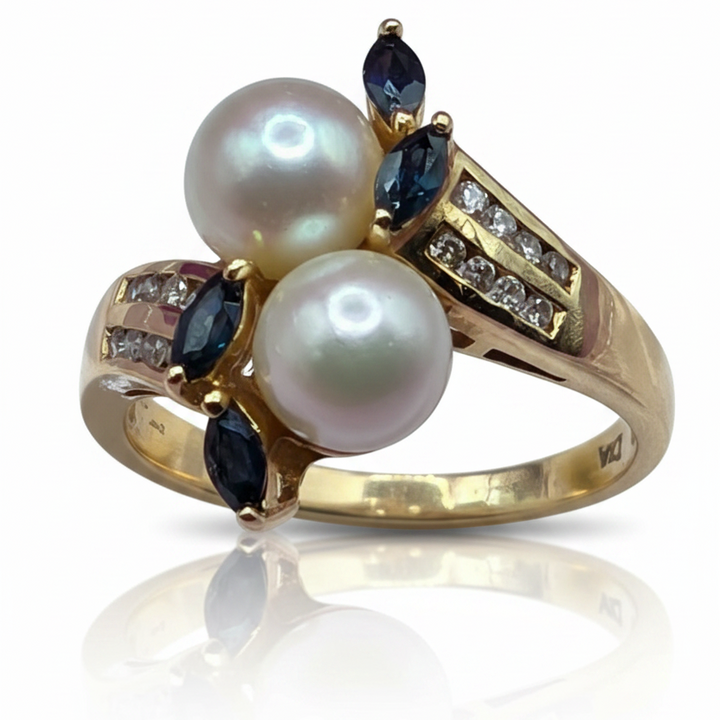 Gold ring with pearls, diamonds and sapphire gemstones on a white satin background