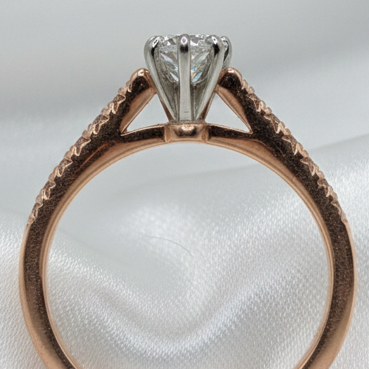 Rose gold ring with a diamond on a white satin background