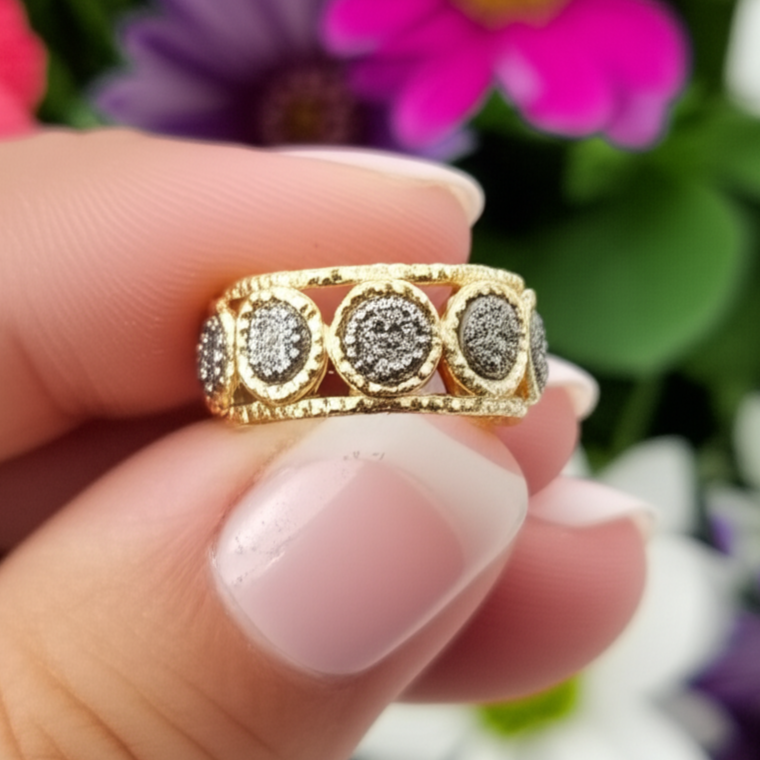 Gold ring with diamonds held between fingers against a floral background