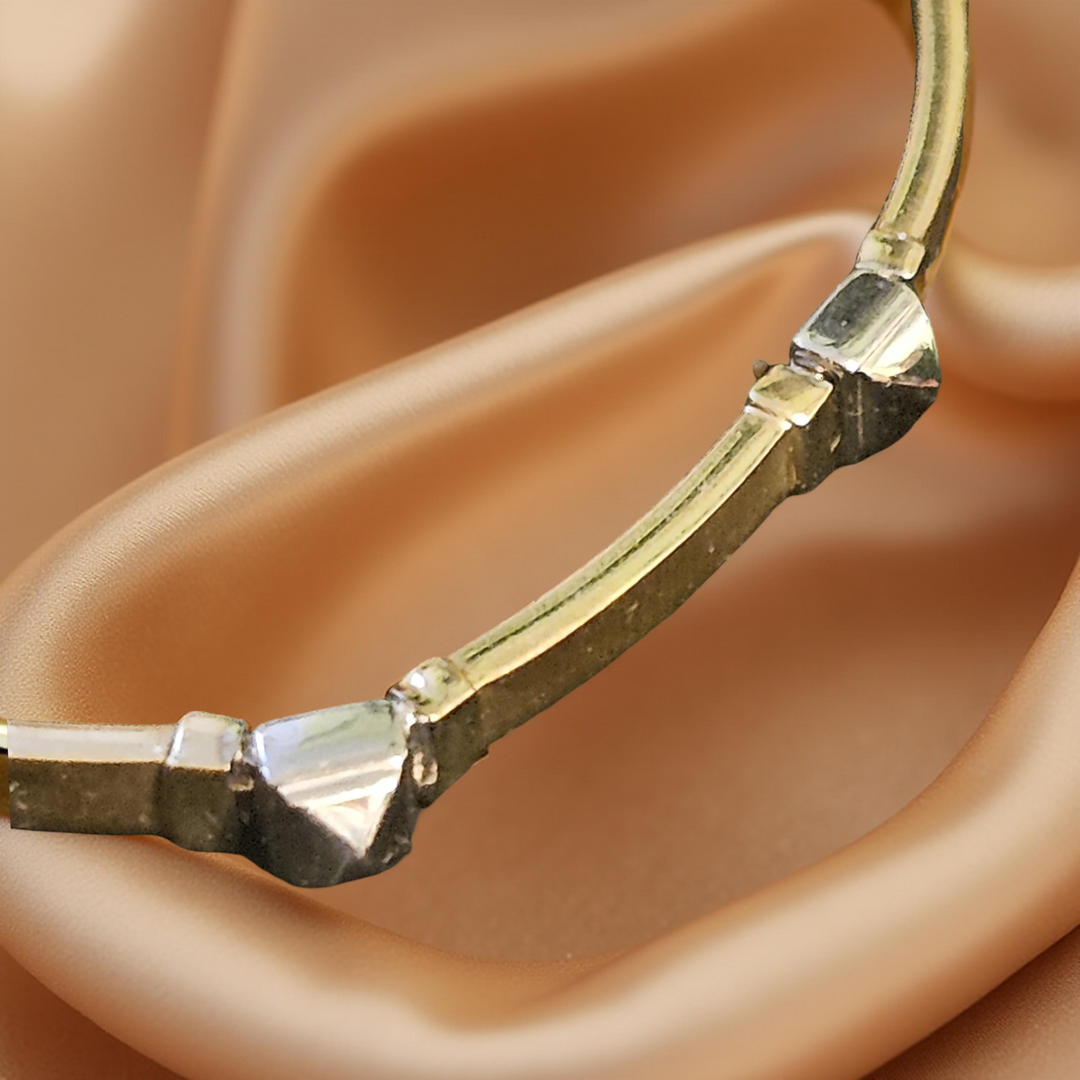 Gold bracelet with diamond-like stones on a beige fabric background