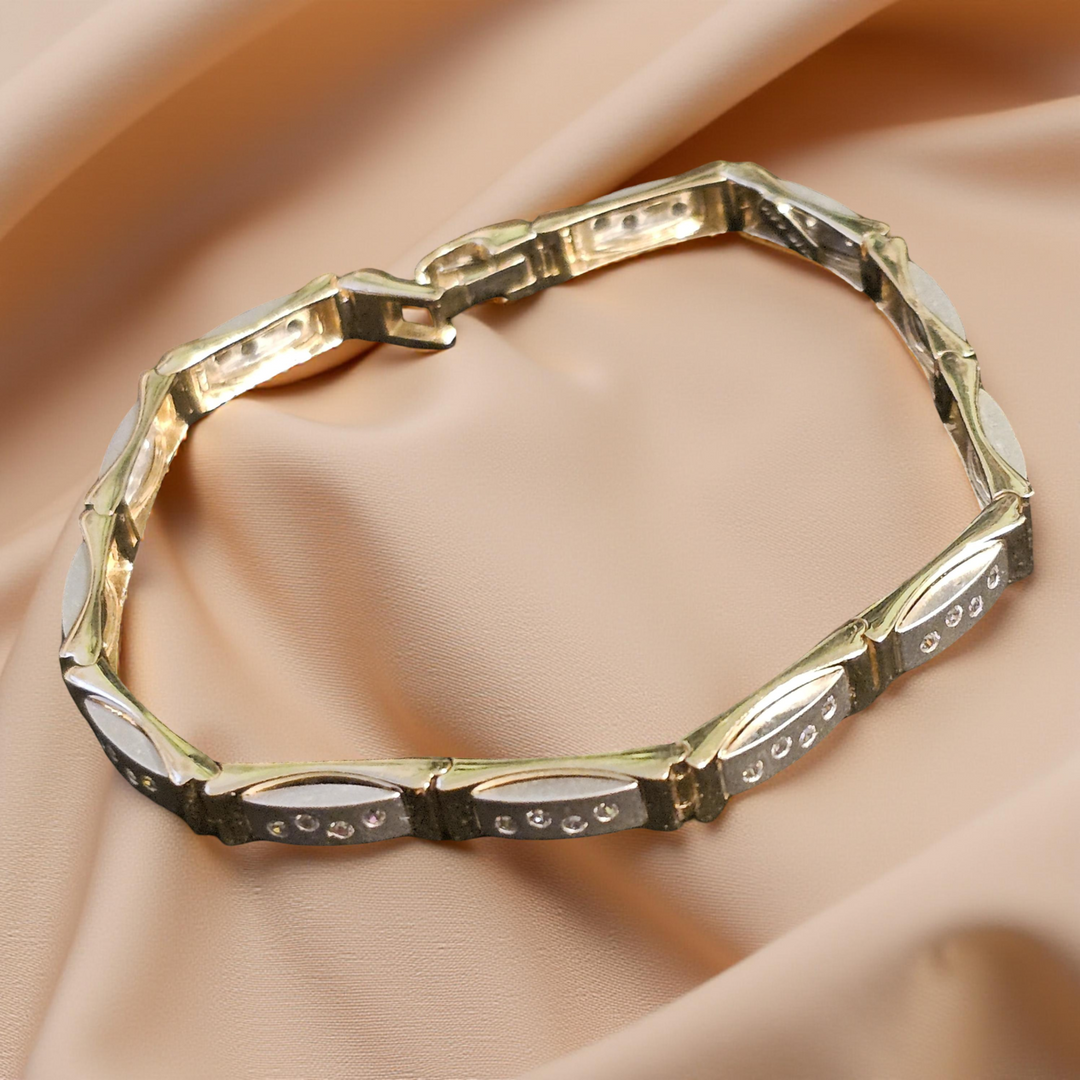 Gold bracelet with diamond accents on a beige fabric background